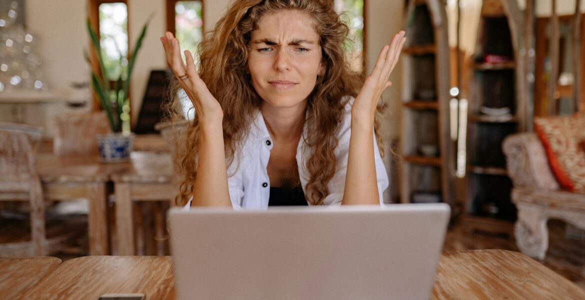 Woman looking at laptop screen and frustrated.